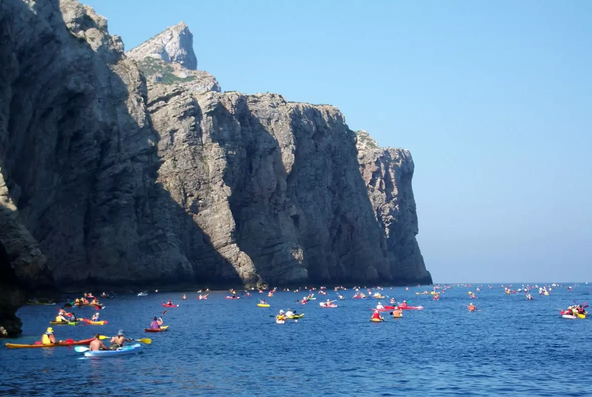 Kayakers paddling near the rocky cliffs of Sa Dragonera island.