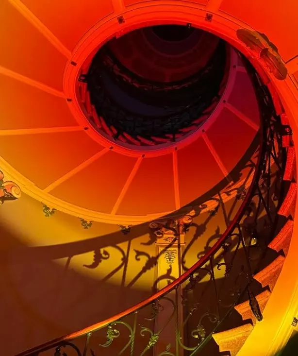 Spiral staircase inside Museum Can Prunera lit in warm red tones