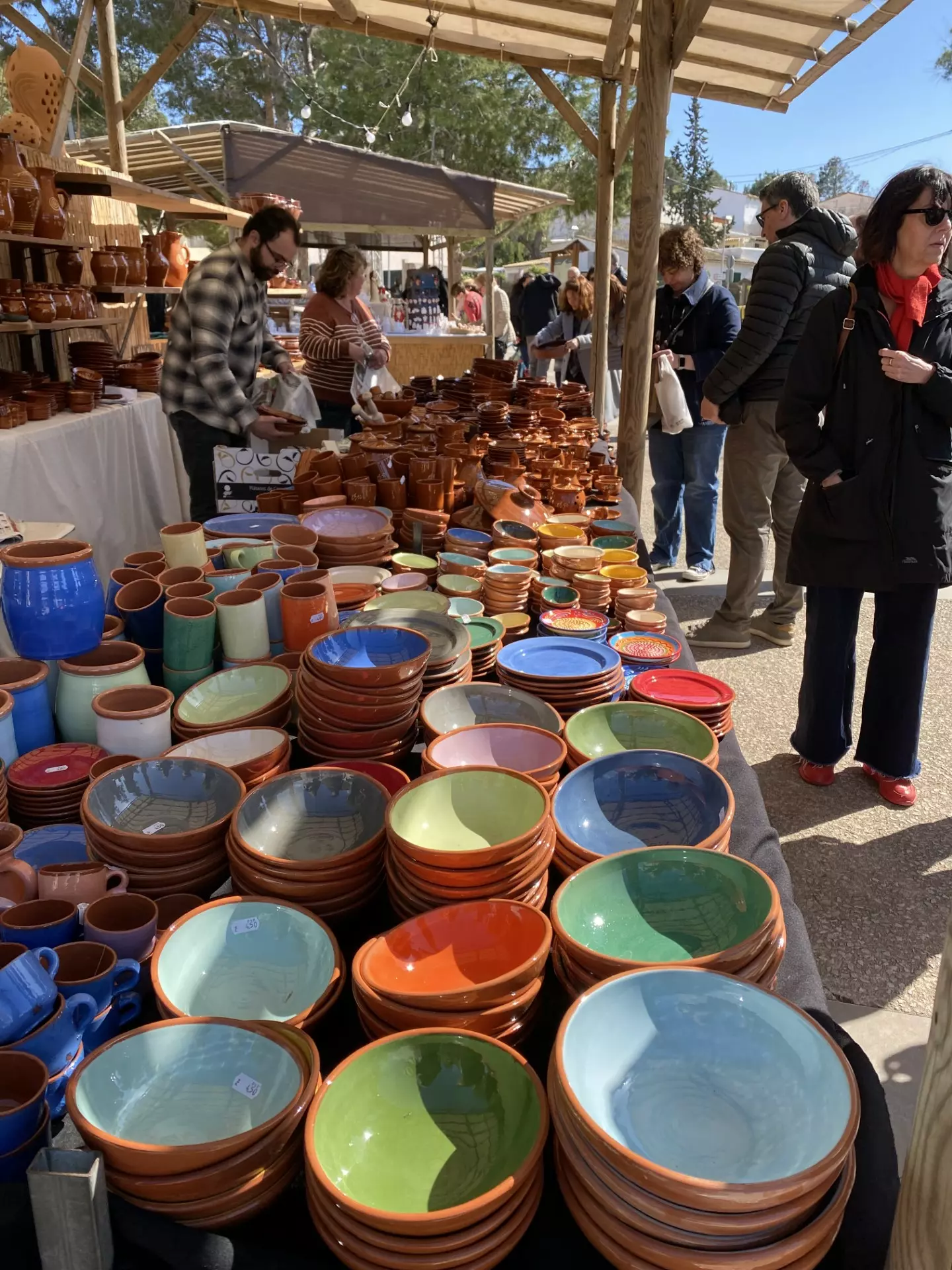 Colourful ceramic bowls and pottery displayed at an outdoor market stall.