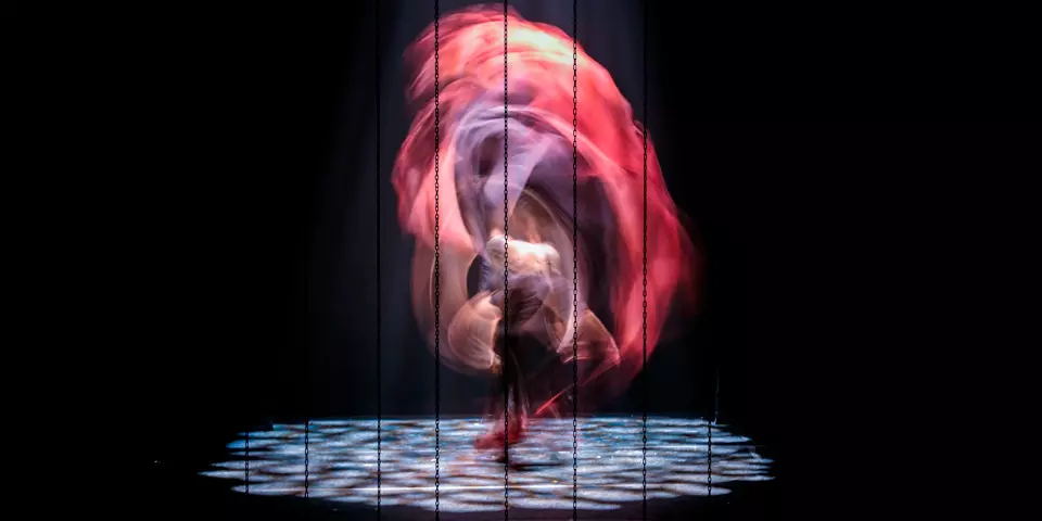 Flamenco dancer performing on stage with flowing red costume
