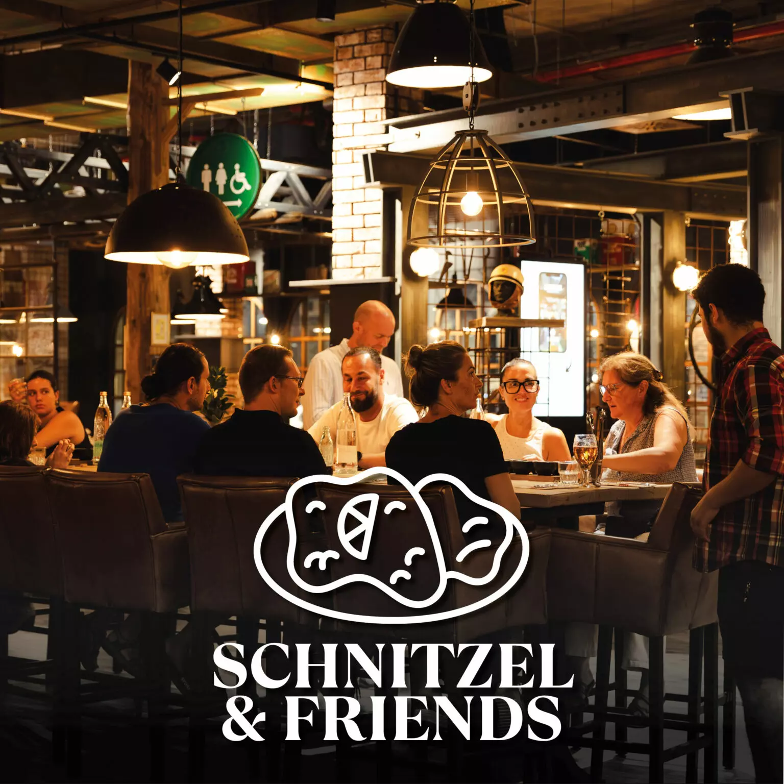 Guests enjoying a group lunch at Schnitzel & Friends in Motorworld Mallorca