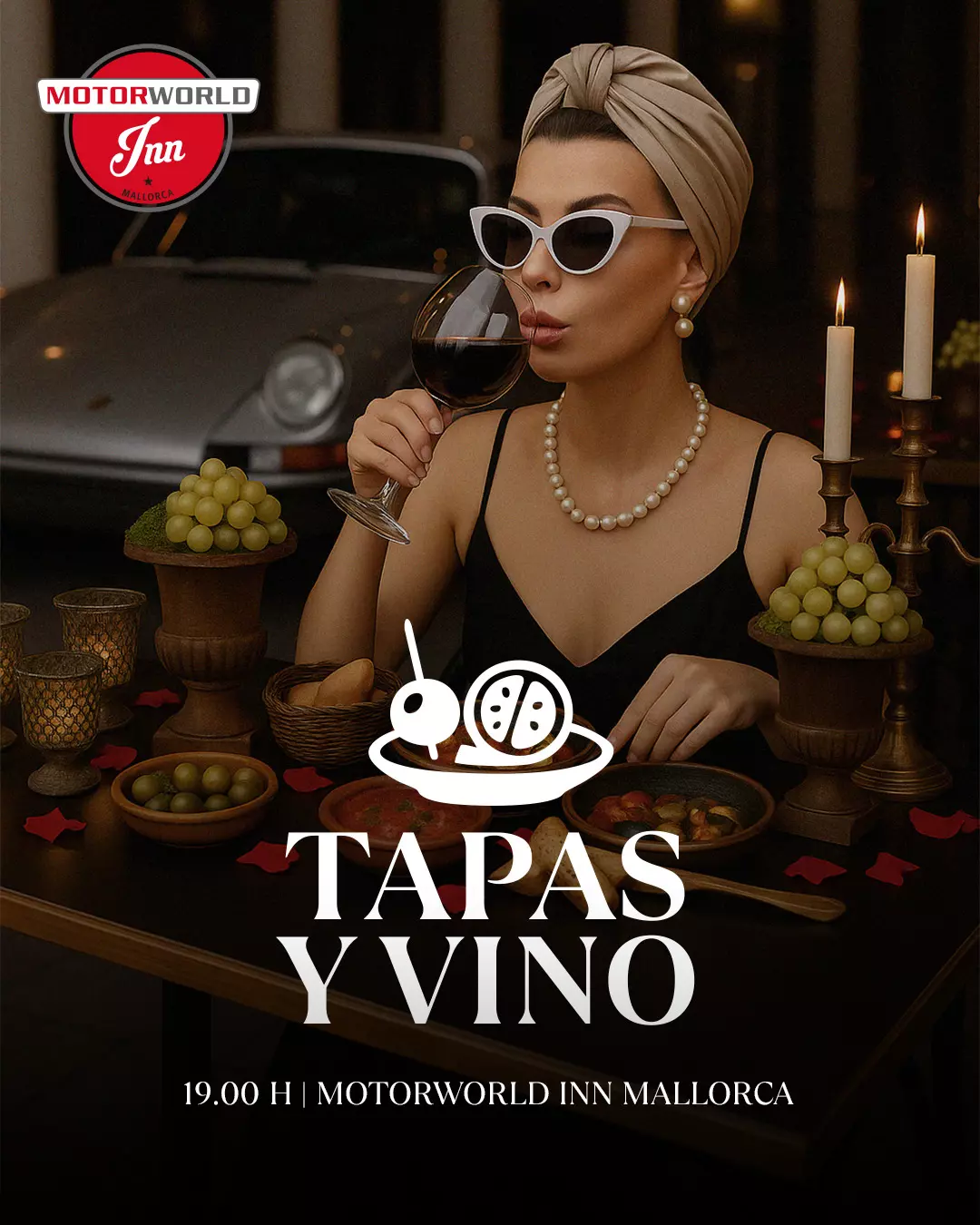 Stylish woman wearing a turban, sunglasses, and pearls enjoys a glass of red wine at a candlelit table with tapas and grapes.