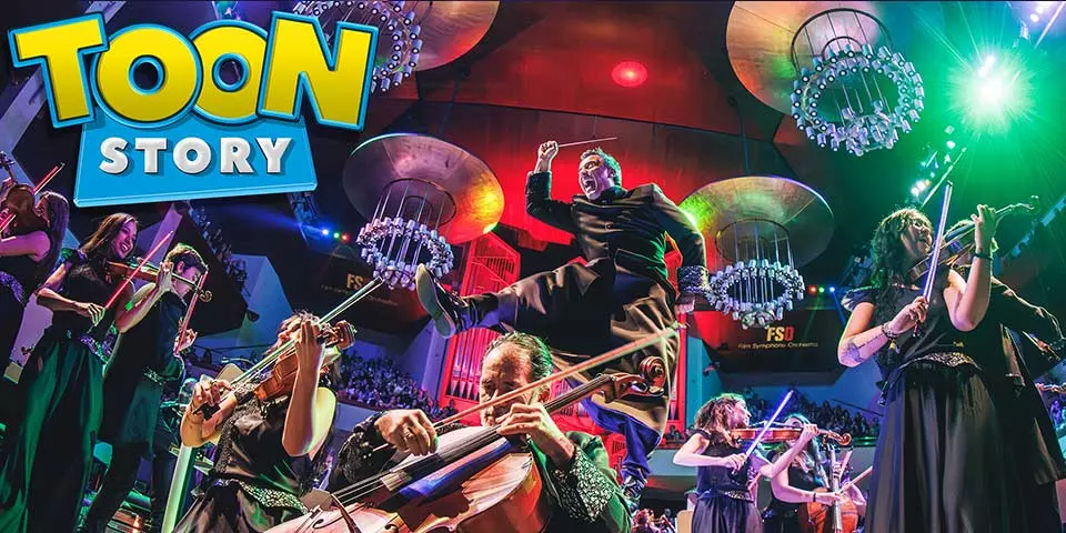 Orchestra performing Disney film music on stage under colourful lights