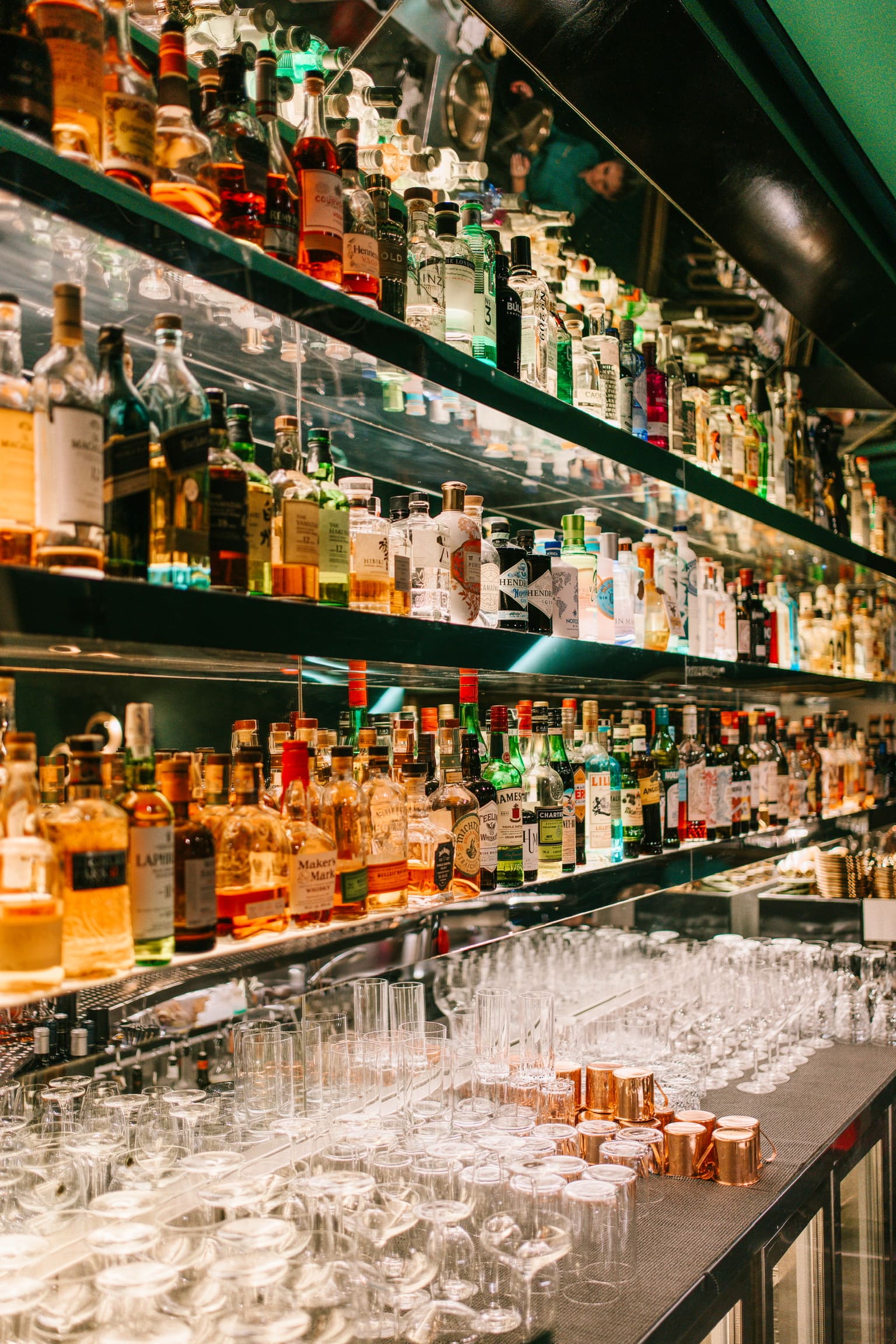 A well-stocked bar with rows of liquor bottles and glasses neatly arranged at Bar Nicolás in Palma de Mallorca.
