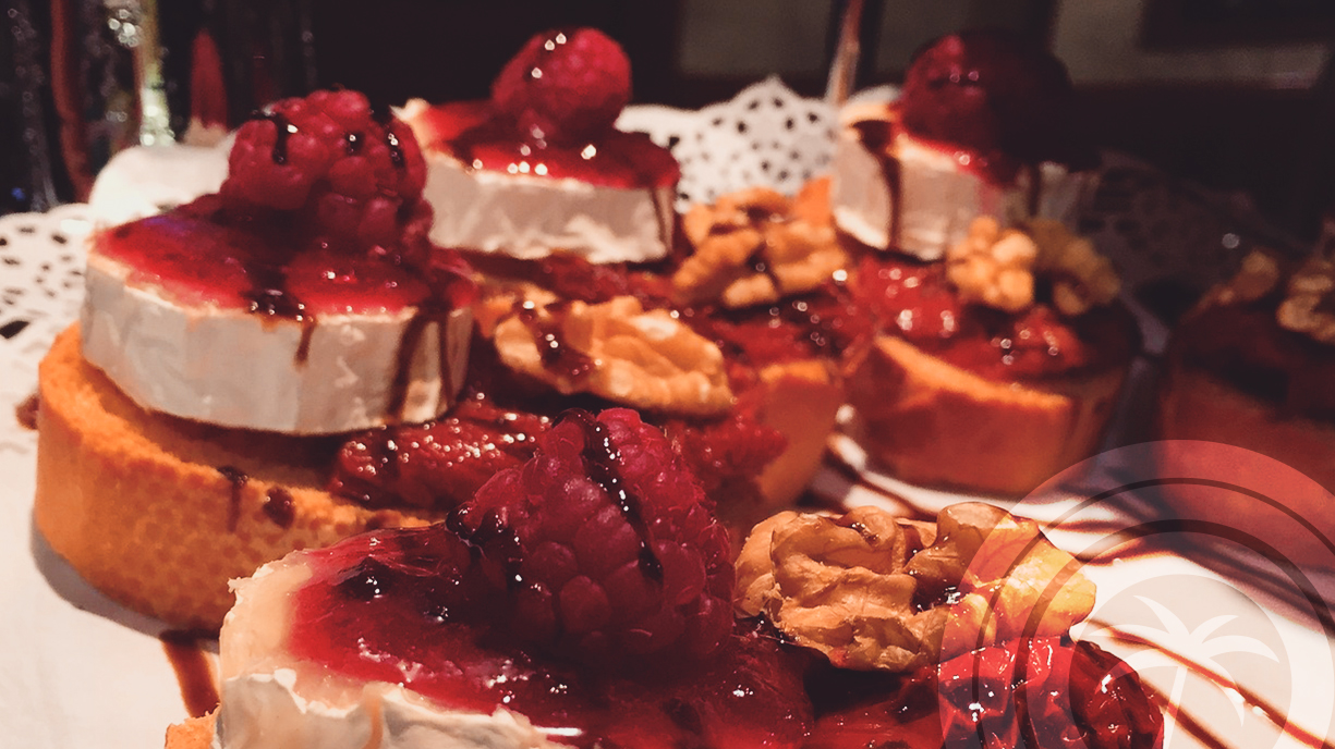 Tapas with cheese, red berries, and walnuts on slices of bread.