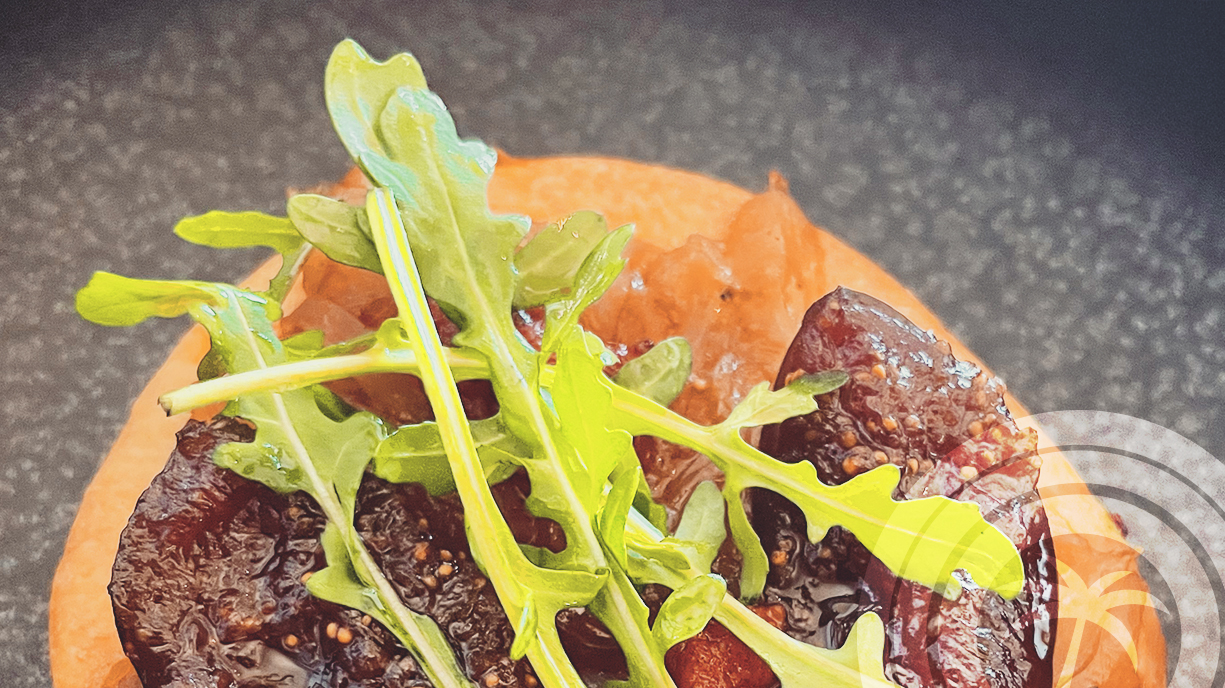 Close-up of a round base topped with dark pieces and green leaves.