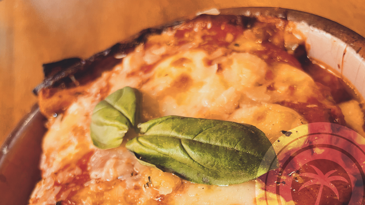 Close-up of a baked Italian dish with melted cheese and basil leaf