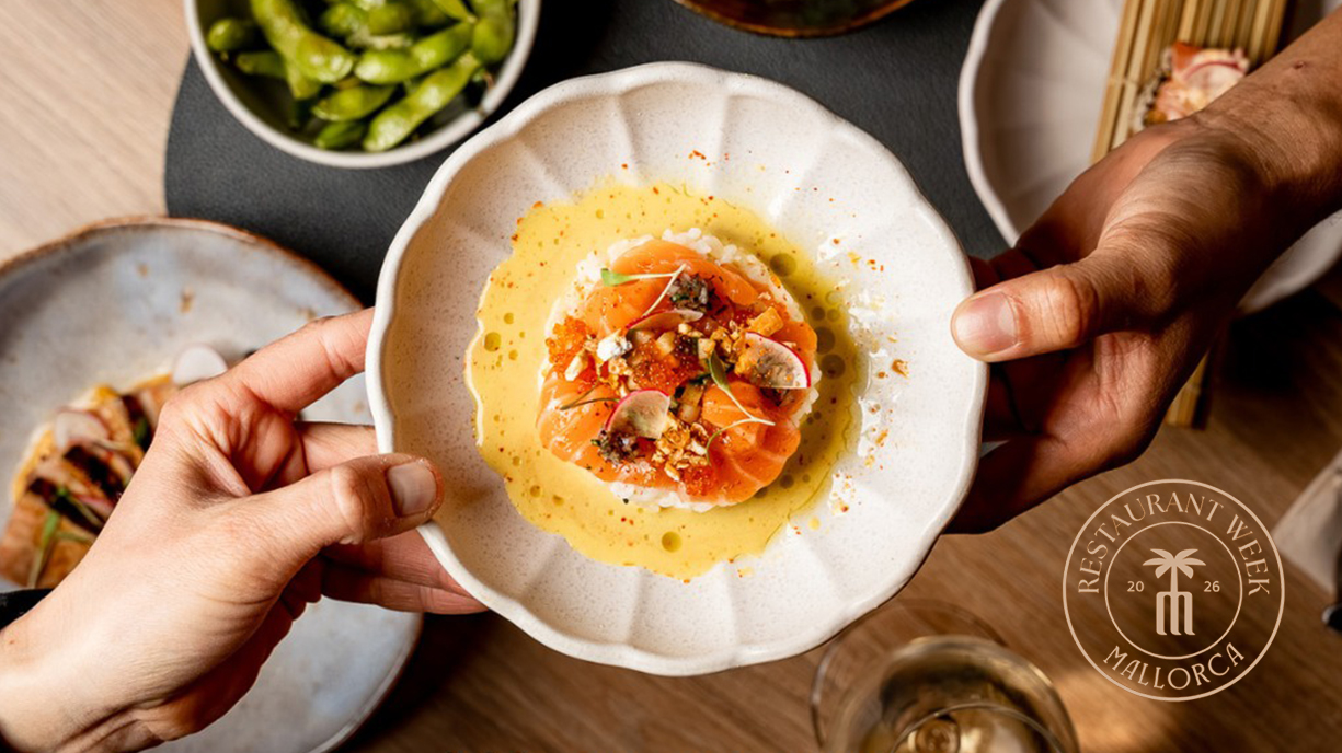 Salmon nigiri in a white bowl with sauce, being handed between two people.