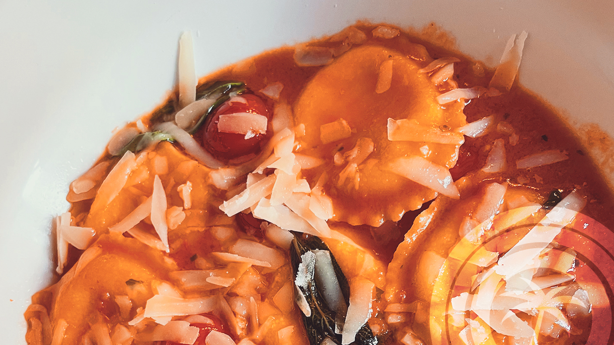 Ravioli in tomato sauce, topped with grated cheese and a few cherry tomatoes.