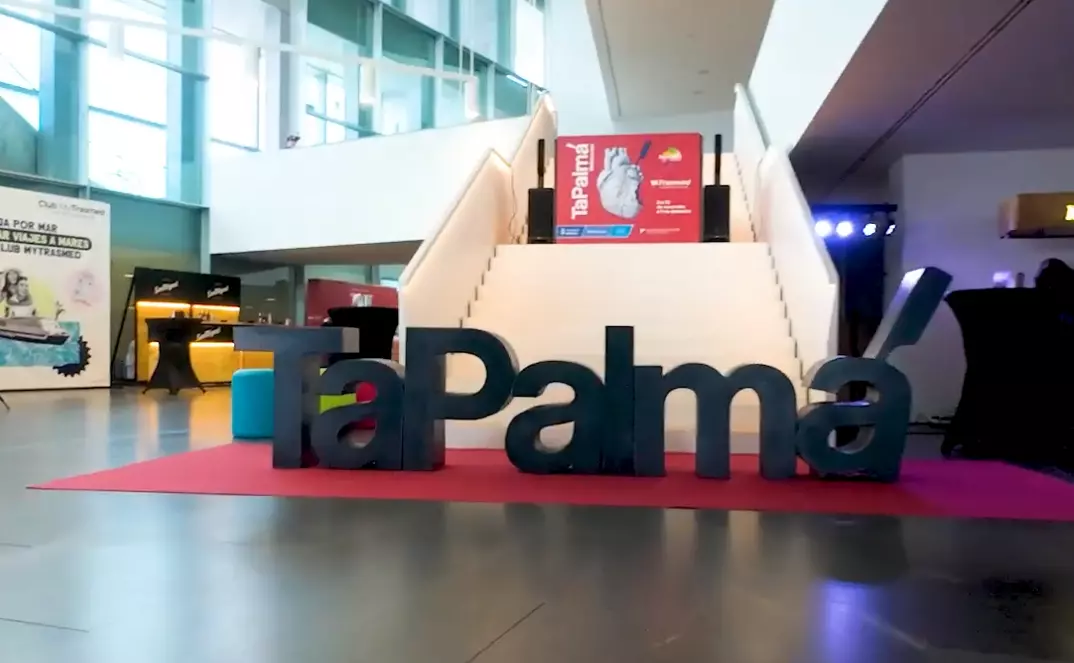 Large TaPalma logo displayed inside a modern hall with glass walls and a staircase in the background, promoting Palma’s annual tapas route event.